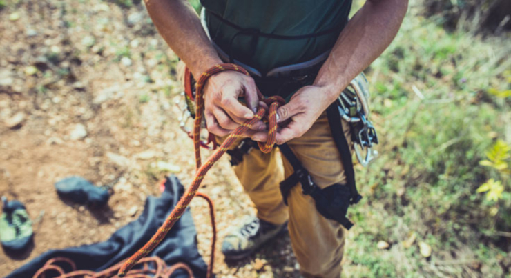 man tying rope around his waist for rock climbing