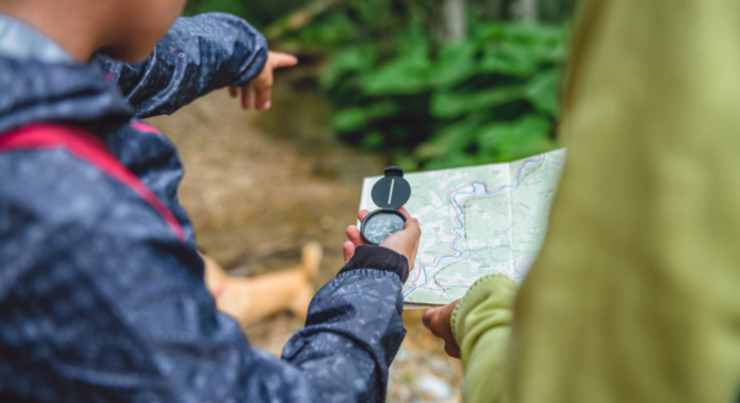 man holding a compass and pointing to the trail ahead