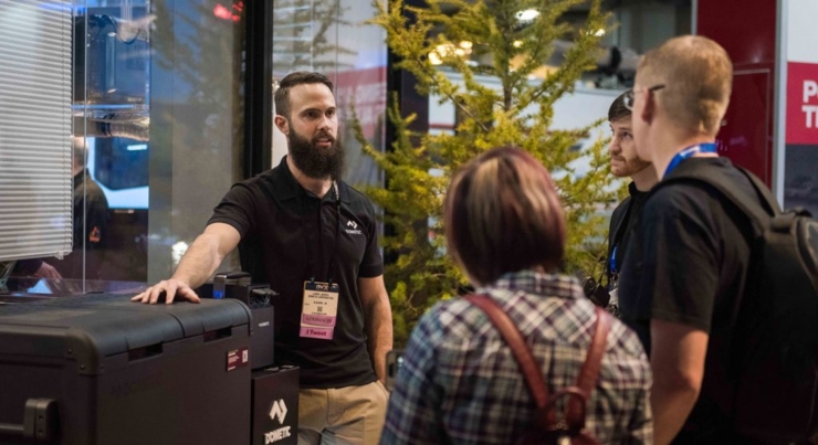 Dometic rep talking to two attendees with his hand on outdoor grill